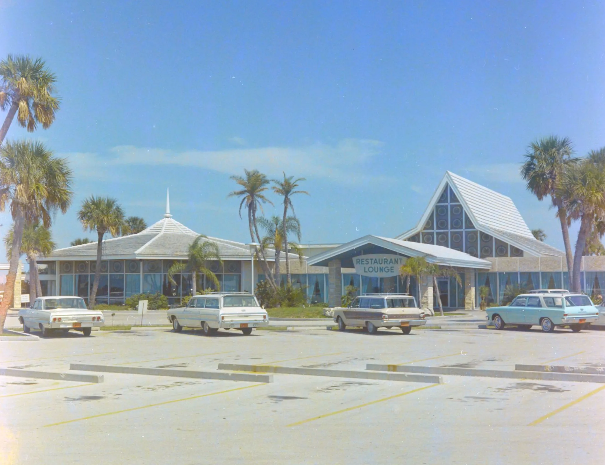 Cars sit in parking lot outside mid-century restaurant