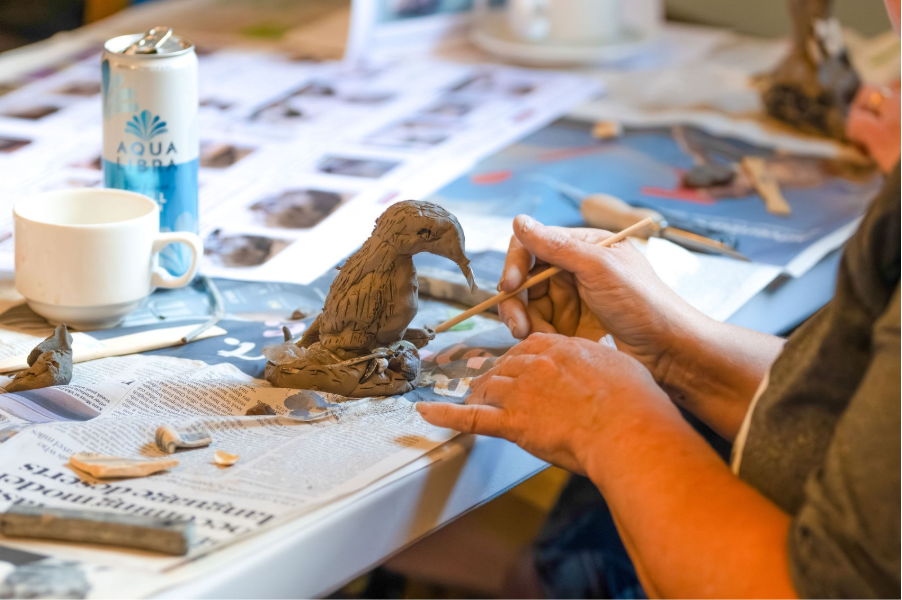 Person sculpting a bird from clay