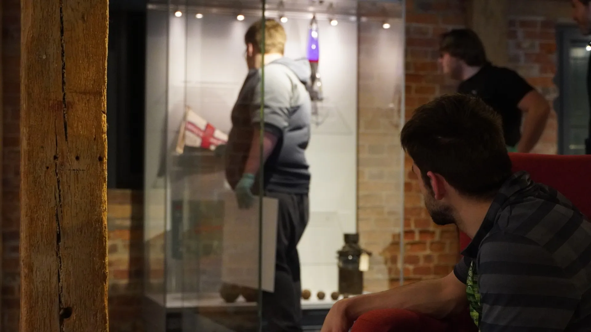Three students assemble items in a glass display cabinet.